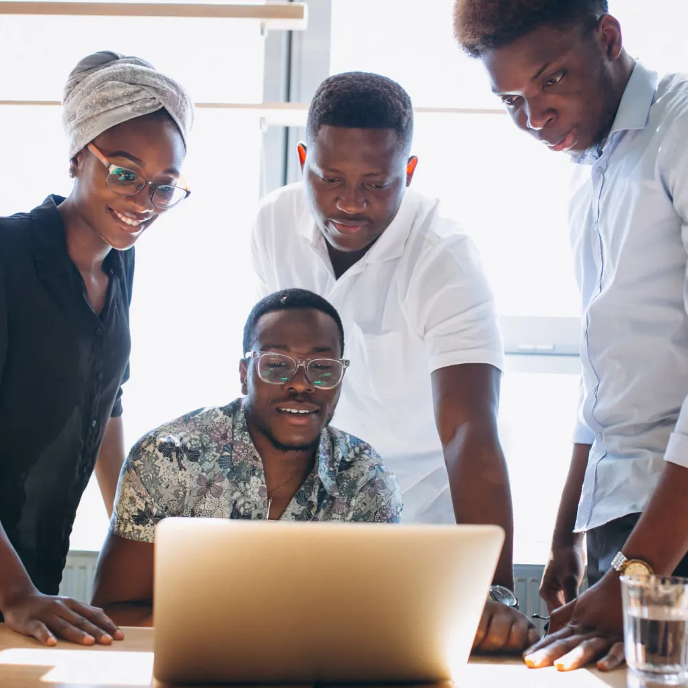 Four Ghanaian students collaborating around a laptop during an InternsHub internship placement in Accra